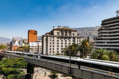 Medellin, Antioquia, Kolombiya. 17 Ocak 2024: Mavi gökyüzü ile Nutibara Oteli ve Medellin metro rayları.
