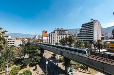 Medellin, Antioquia, Kolombiya. 17 Ocak 2024: Mavi gökyüzü ile Nutibara Oteli ve Medellin metro rayları.