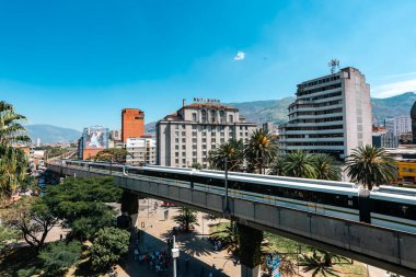 Medellin, Antioquia, Kolombiya. 17 Ocak 2024: Mavi gökyüzü ile Nutibara Oteli ve Medellin metro rayları.
