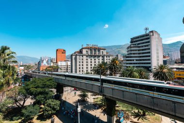Medellin, Antioquia, Kolombiya. 17 Ocak 2024: Mavi gökyüzü ile Nutibara Oteli ve Medellin metro rayları.