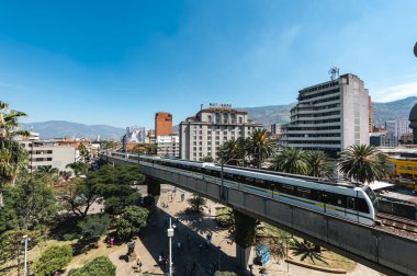 Medellin, Antioquia, Kolombiya. 17 Ocak 2024: Mavi gökyüzü ile Nutibara Oteli ve Medellin metro rayları.