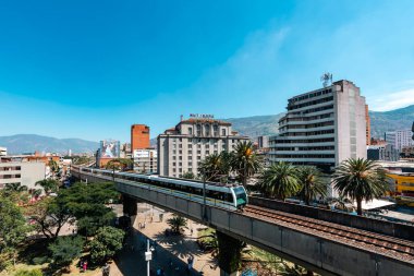 Medellin, Antioquia, Kolombiya. 17 Ocak 2024: Mavi gökyüzü ile Nutibara Oteli ve Medellin metro rayları.