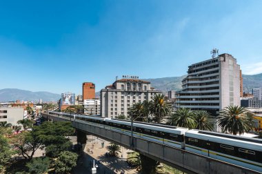 Medellin, Antioquia, Kolombiya. 17 Ocak 2024: Mavi gökyüzü ile Nutibara Oteli ve Medellin metro rayları.