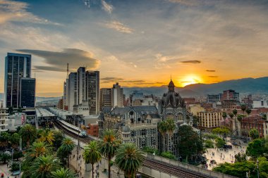 Medellin, Antioquyia, Colombia. January 17, 2024: Rafael Uribe Palace of Culture and metro station with beautiful colorful sunset in the city. clipart