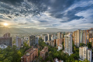 Medelin, Antioquia, Kolombiya. 27 Ağustos 2024: Ufukta güneş ve şehir manzaralı HDR manzarası.