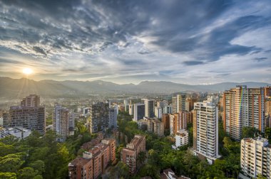 Medelin, Antioquia, Kolombiya. 27 Ağustos 2024: Ufukta güneş ve şehir manzaralı HDR manzarası.