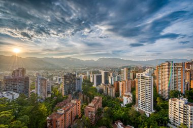 Medelin, Antioquia, Kolombiya. 27 Ağustos 2024: Ufukta güneş ve şehir manzaralı HDR manzarası.