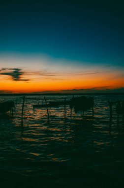 Cispata Körfezi 'nde insan ve tekne siluetleriyle portakal rengi gün batımı. Kolombiya. 