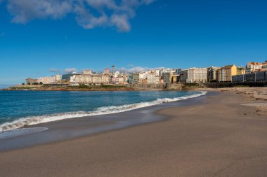 La Coruna, İspanya. 11 Kasım 2024: Orzan sahilinde mavi gökyüzü ve binalar.