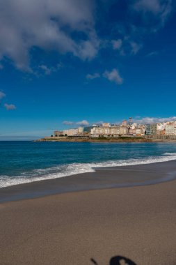 La Coruna, İspanya. 11 Kasım 2024: Orzan sahilinde mavi gökyüzü ve binalar.