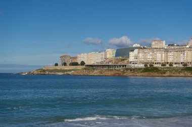 La Coruna, İspanya. 11 Kasım 2024: Orzan sahilinde mavi gökyüzü ve binalar.
