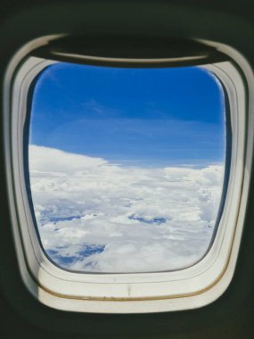 Bir uçak penceresinden bulutların yükseldiği güzel gökyüzü manzarası.