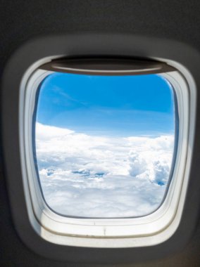 Bir uçak penceresinden bulutların yükseldiği güzel gökyüzü manzarası.