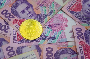 Golden bitcoin on two hundred ukrainian hryvnia bills background. Ukrainian grivna to Bitcoin concept