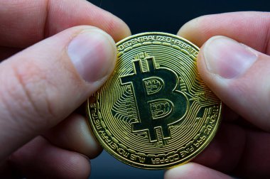 Bitcoin transfer concept from hand to hand. High quality photo. Finger hold bitcoin golden on black isolated. Hand hold gold bitcoin crypto digital money
