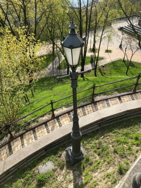 Scenic bright sunrise in park with pedestrian walkway and lantern. Top view. An old lantern in a summer park in the morning