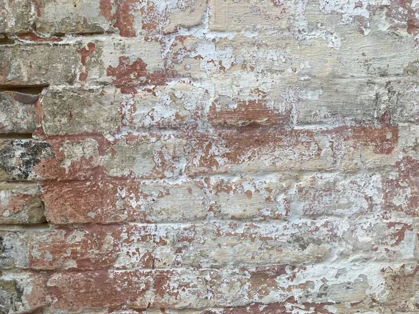 Old multi colored brick wall. Background of old vintage dirty brick wall with peeling plaster, texture