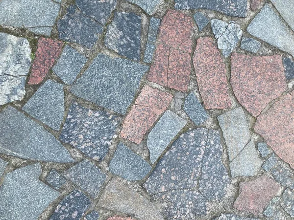 decorative stone floor texture on the terrace. Granite dirty paving stones in the city. Road from paving stones for background and texture. The old road of granite paving stones
