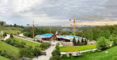 Construction site, three tall tower cranes and blue building materials. Memorial to the victims of the Holodomor in Ukraine. A view of the construction site of the new complex