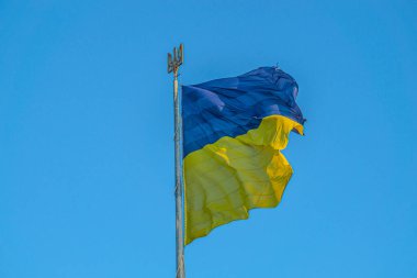 Ukrayna amblemi. Mavi gökyüzünde dalgalanan Ukrayna bayrağı. Büyük sarı Ukrayna bayrağı. Ulusal Ukrayna bayrağı mavi gökyüzüne karşı. Ukrayna bayrağının ayrıntıları. Ukrayna Amblemi