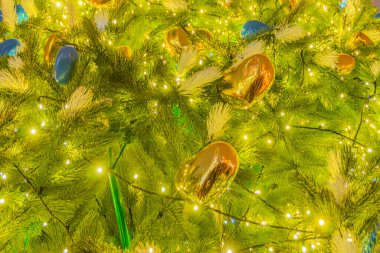 Kalp şeklindeki süslerle süslenmiş bir Noel ağacının arka planı. Sarı altın ışıklı Noel ağacı süslemesi