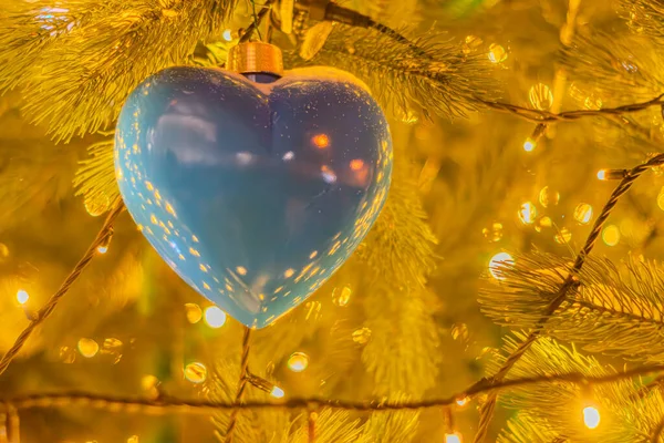background of a decorated Christmas tree with heart-shaped ornaments. Christmas tree decoration with yellow gold lights background