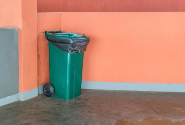 Temizlik, atık ayırma ve kamu hijyeni kavramı. Çimento zemininde turuncu duvar zeminli çöp kutusu, geri dönüşüm konsepti.