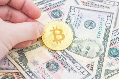 Erkek eli. Bitcoin nakit BTC, kripto para olarak resmedilmiş altın, doların üzerinde duran altın para, gerçek Amerikan parası, 50 dolar, 50 dolar. ABD Doları Banknotlarının Üzerinde Bitcoin.