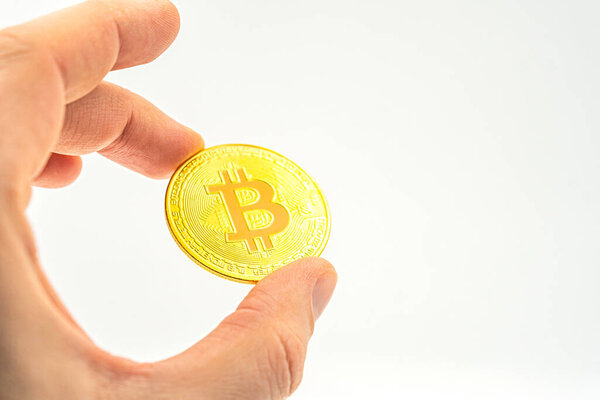 Крупный план держания биткойна криптовалюта, будущий бизнес. Новые технологии и криптовалюты, а также инвестиции в добычу полезных ископаемых и сокращение вдвое. Рука держит золотой биткойн на белом фоне.