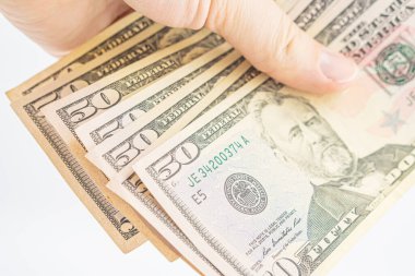Elinde birkaç tane 50 dolarlık banknot var. Beyaz arka planda izole edilmiş dolarları olan bir adam. İş adamı elli dolar verir. Amerika 'da bahşiş ve nakit kavramı. Bir tomar dolar, rüşvet, yasadışı trafik.