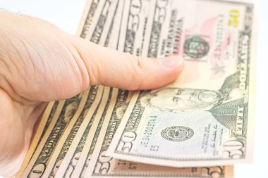 Elinde birkaç tane 50 dolarlık banknot var. Beyaz arka planda izole edilmiş dolarları olan bir adam. İş adamı elli dolar verir. Amerika 'da bahşiş ve nakit kavramı. Bir tomar dolar, rüşvet, yasadışı trafik.