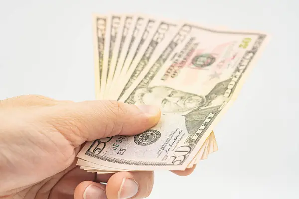 Several 50 dollar bills in hand. Man hand with dollars isolated on a white background. Businessman gives fifty dollars. Concept of tips and cash in America. A bundle of dollars, bribe, illegal traffic