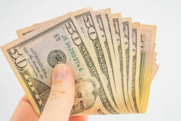 Several 50 dollar bills in hand. Man hand with dollars isolated on a white background. Businessman gives fifty dollars. Concept of tips and cash in America. A bundle of dollars, bribe, illegal traffic
