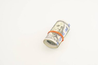 Beyaz arka planda izole edilmiş 100 dolarlık banknotlar. Beyaz arka planda izole edilmiş yuvarlanmış para. Beyaz arka planda izole edilmiş dolar. Kırmızı kurdeleyle sarılmış dolar rulosu.
