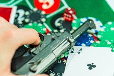 Poker masasında kelepçe ve silah. Kumarhane suçu konsepti, yeraltı kumarhaneleri. Yasadışı oyunlar, kumar konsepti. Masada, zarlı, paralı ve fişli iskambil kağıtları var. Kumarhane konsepti, oyunlar