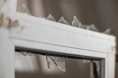 Askeri bombardımanın yol açtığı yangın sırasında camı kırmış. Yakın planda kırık bir konut penceresi. Kirli cam kırıkları dışında kırık camlar. Rus-Ukrayna savaşı