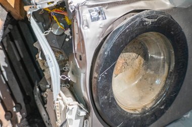 Hasarlı çamaşır makinesini kontrol eden kadın, dairedeki yangından sonra zemini su basmış, çamaşır makinesi bozulmuş..