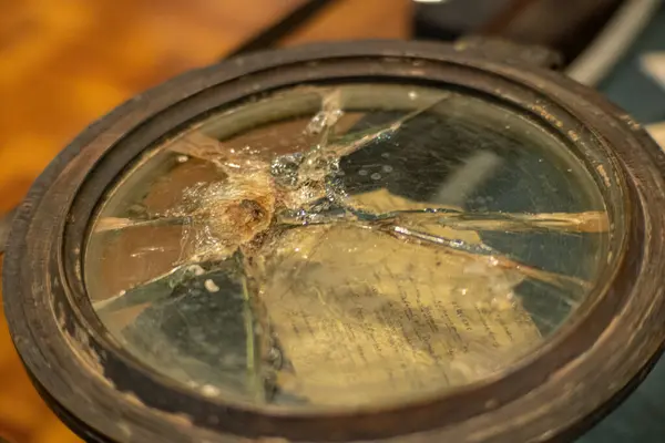 stock image Broken glass on a compass or porthole on a wartime ship. Reflected, distorted and refracted light