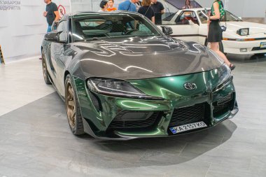 Yeşil bir spor araba, parlak tasarımı ve aerodinamik özelliklerinin vurgulandığı bir otomobil fuarı veya sergisinde sergileniyor. Araç I Kyiv, Ukrayna 06-06-2024