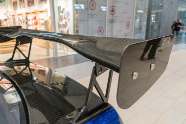 A carbon fiber rear wing is mounted on the back of a sports car, visible against an artificial indoor background The wing has two adjustable flaps su Kyiv, Ukraine 06-06-2024 clipart