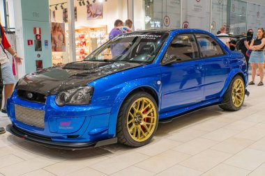 A blue modified car stands center stage, surrounded by a crowd in the background, showcasing a wide-body kit with flared fenders and a large front bum Kyiv, Ukraine 06-06-2024 clipart