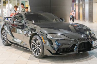 A black sports car is positioned at an angle on display indoors, showcasing its sleek bodywork, wide wheel arches, large alloy wheels with low-profile Kyiv, Ukraine 06-06-2024 clipart