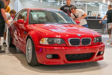 Kırmızı bir BMW Z4, arka planda belirgin bir BMW işareti bulunan kapalı bir etkinlikte, dikkatleri Ukrayna, Kyiv, Ukrayna 06-2024 'e çeken geniş bir arkaplanda görüntülenir.