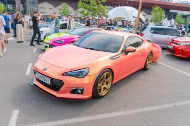 Pembe parlak bir spor araba, düşük profilli duruşu, altın aksanlı geniş alaşımlı tekerlekleri, aerodinamik yan etekleri, geniş gövdeli kiti, ve p Kyiv, Ukrayna 06-06-2024