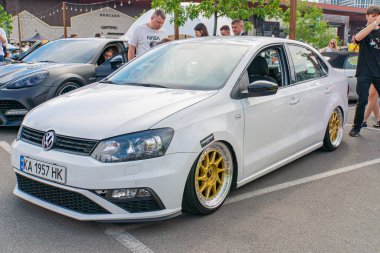 Yolun kenarına park edilmiş beyaz bir hatchback arabası, geniş sarı çerçeveli tekerlekler, vücut kiti bileşeni Kyiv, Ukrayna 06-06-2024 'ü kapsayan ayırt edici modifikasyonlar sergiliyor.