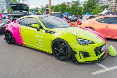 A vibrant, modified sports car with bright yellow body color and pink stripes parked on the street, showcasing an aerodynamic body kit, large black wh Kyiv, Ukraine 06-06-2024 clipart