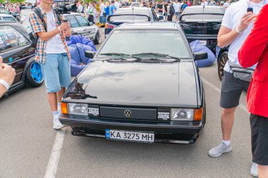 Geniş gövdeli modifikasyonlara ve pazar sonrası tekerleklerine sahip siyah bir Volkswagen Golf GTI, bir açık hava otomobil fuarı ayarında asfalt bir yüzeye park edilmiş, Kyiv, Ukrayna 06-06-2024