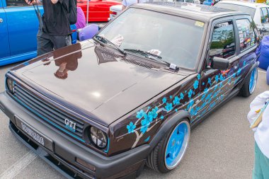 Modifiye edilmiş küçük bir hatchback araba bir araç fuarı veya sergisinde sergileniyor. Arabanın koyu renkli ve parlak bir kaplama, düşük süspansiyonlu, ai Kyiv, Ukrayna 06-06-2024