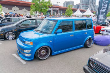 A custom-painted blue van is parked among several other vehicles, its body kit featuring modified bumpers and side skirts The hood has a scoop for im Kyiv, Ukraine 06-06-2024 clipart