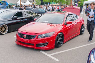 Diğer araç ve yayalarla çevrili halka açık bir yola park edilmiş canlı kırmızı spor bir araba, büyük Kyiv, Ukrayna 06-06-2024